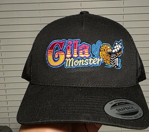 Black Yupoong trucker with a bright neon pink, blue and yellow Gila Monster logo