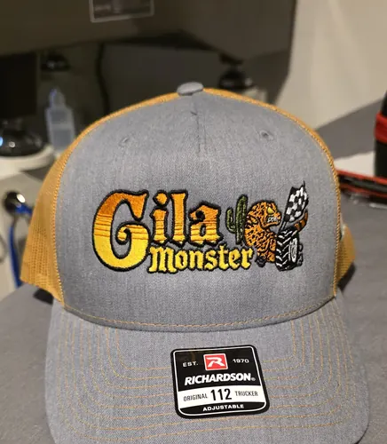 Grey and gold Richardson 112 trucker with a colorful embroidered Gila Monster logo