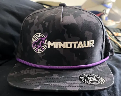 Black camo 5-panel snapback with a purple rope, embroidered with a purple and white bull medallion and a white MINOTAUR wordmark