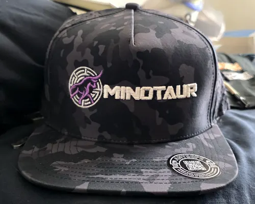 Front view of a black camo flat-bill snapback embroidered with a purple and white bull medallion and a white MINOTAUR wordmark