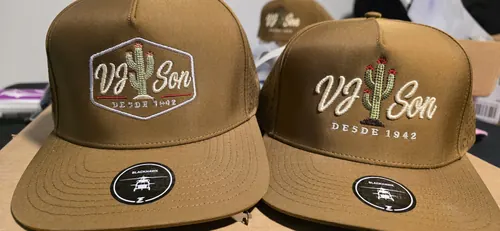 Two tan caps, one with the VJ Son hexagon badge and one with the VJ Son cactus script logo